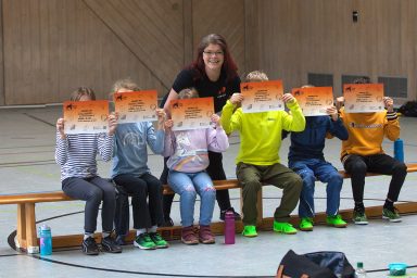 Helen Häge mit einer Gruppe von Kindern, die ihre Urkunden hochhalten