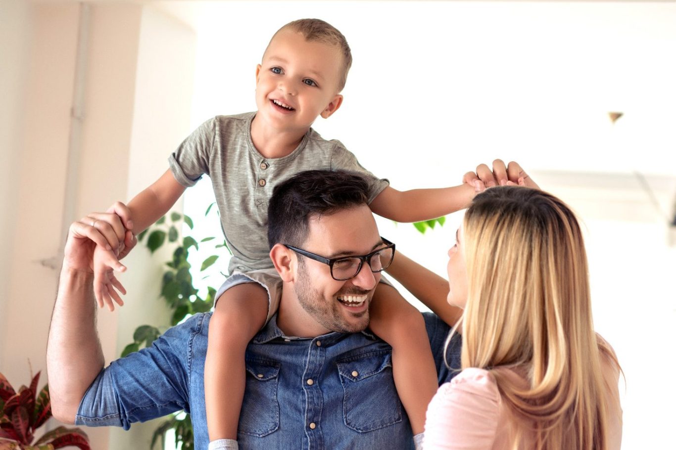 Vater trägt lachenden Sohn auf den Schultern, während die Mutter glücklich zusieht.